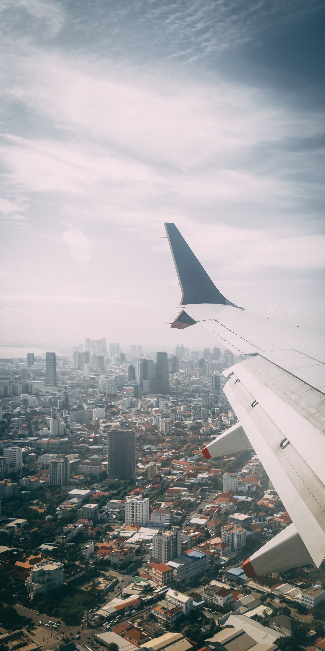 Cityscape from airplane window with skyline in the distance, urban aerial perspective.